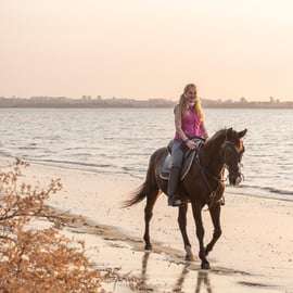Cavalcare sulla spiaggia al tramonto