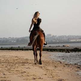 Cavalcare sulla spiaggia al tramonto